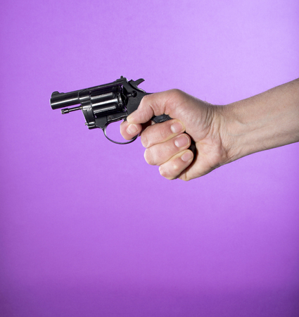 Revolver in a man's hand on a purple backgroundの写真素材