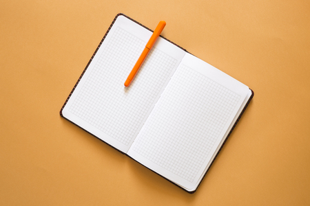 Open notebook with pen on yellow background, top viewの写真素材