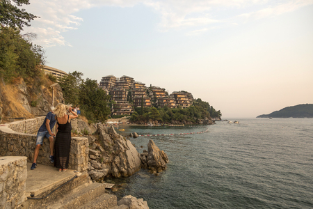 Budva, Montenegro - August 05, 2017: The guy and the girl take pictures on the smartphone surrounding landscapeのeditorial素材