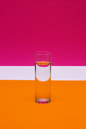 Glass with a glass of liquid on a colored background