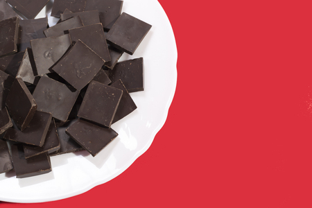 White plate with chocolate on a red backgroundの写真素材