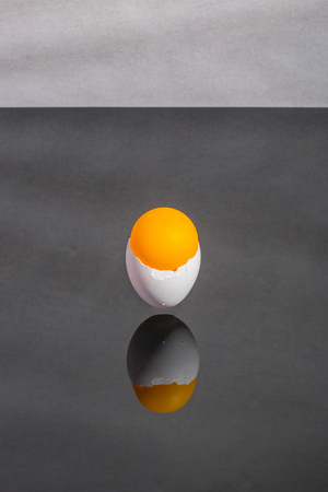 Eggshell stuck in the air above the table with an orange ballの写真素材