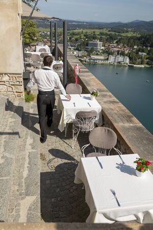 Bled, Slovenia - August 15, 2019: Fragment of a cafe with a waiter on the territory of Bled Castle on the background of a lake in Sloveniaのeditorial素材