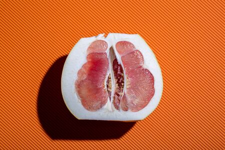 Sliced ââpomelo fruit on an orange background close-upの写真素材