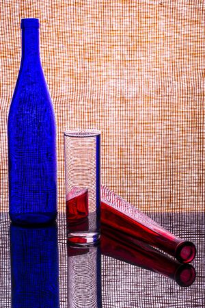 Still life with a glass of water, a red and blue bottleの写真素材