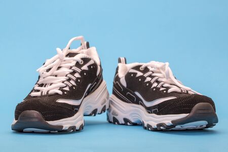 Black and white women's sneakers on a blueの写真素材