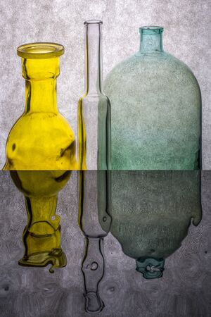 Still life with colored bottles on a reflective surfaceの写真素材