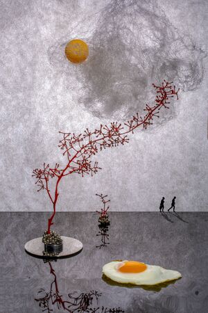 Installation with people silhouettes, fried eggs, sun, cloud and branchesの写真素材