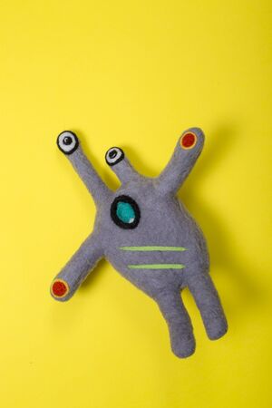 Fantastic creature soft toy made of natural wool on a yellowの写真素材