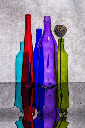 Still life with colored bottles on a reflective surfaceの写真素材