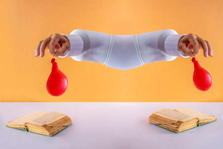 Collage of a man's hand holding a deflated balloon over a bookの写真素材