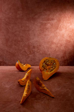 Pieces of cut Hokkaido pumpkin on brown backgroundの写真素材