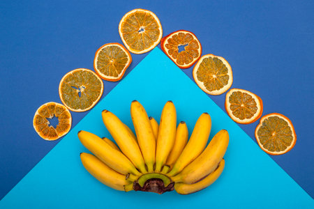 Yellow, ripe mini bananas and dried lemons on a blue background
