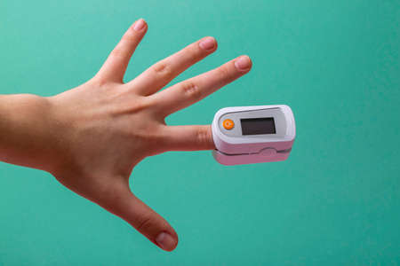Hand of teenager measures pulse and blood oxygen saturation with pulse oximeterの写真素材