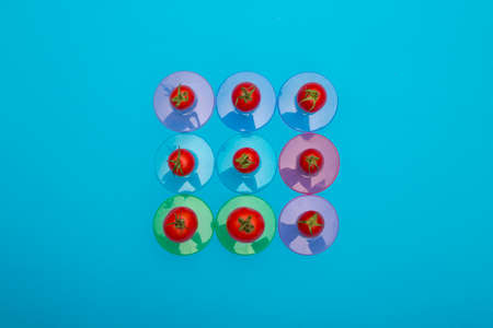 Red ripe tomatoes on colored coasters on a blue backgroundの写真素材