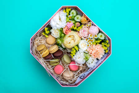 Gift bouquet of flowers with cookies in a pink box on a turquoise background, top viewの写真素材