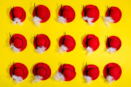 Fifteen felted wool hats with a feather on a yellow background