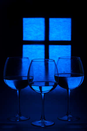 Still life with glass goblets with liquid against the background of a glowing window silhouetteの写真素材