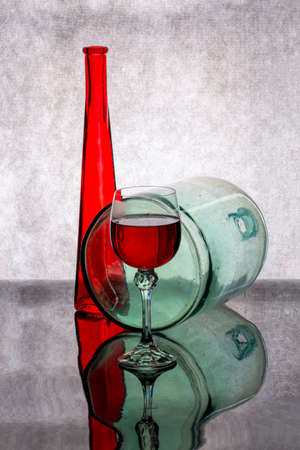 Still life with a red bottle, a glass of red wine and a glass bottleの写真素材