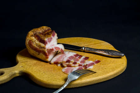 Still life with chopped lard, knife and fork on a kitchen boardの写真素材