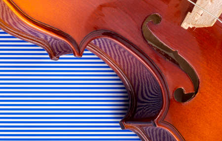 Fragment of violin on blue striped background, close-up