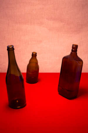 Still life with tilted bottles on a red table