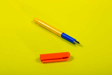 Yellow fountain pen with orange cap on yellow backgroundの写真素材