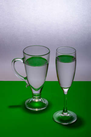 Still life with two glasses of clear liquid on a green tableの写真素材