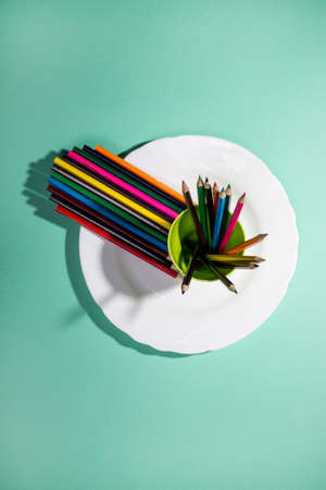 A set of colored pencils on a white plate, top viewの写真素材