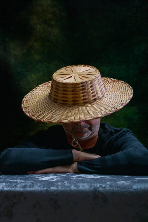 Sleeping man in a wide straw hat at the tableの写真素材