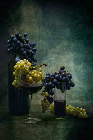 Glasses of red wine and bunches of grapes on a dark backgroundの写真素材