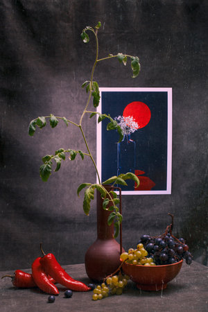 Tomato seedling with pepper, fruit and a bunch of grapes and a picture with a still lifeの写真素材