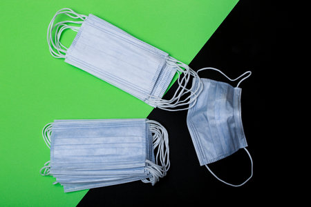 A set of disposable medical masks on a black and green background
