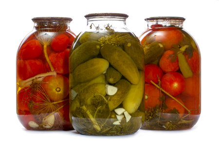 Glass jars with canned tomatoes and cucumbers on a white backgroundの写真素材