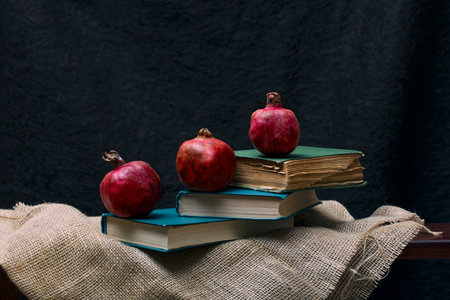 Ripe red pomegranates with books on the shelf