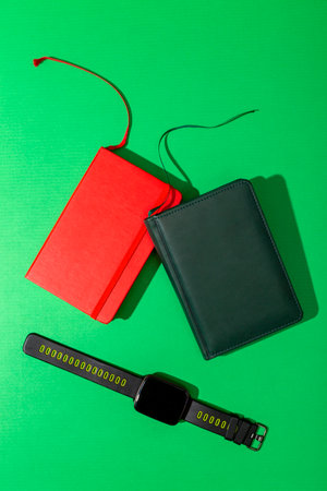Two notebooks and a smart watch on a green background, top viewの写真素材
