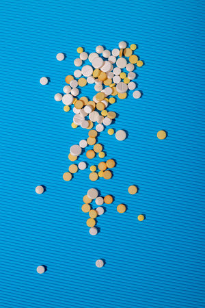 Scattered pills on a blue background, top view