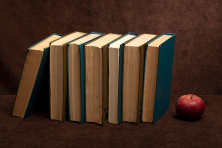 Still life with a stick of old books and an apple on the tableの写真素材