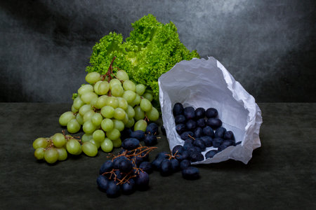 A bunch of ripe grapes with green lettuce leaves on a dark backgroundの写真素材