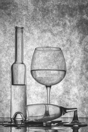 Black and white still life with bottles and a broken glassの写真素材