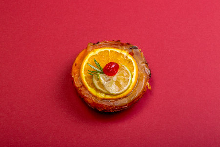 Cheese cake with marmalade and lime and orange slices on a red backgroundの写真素材