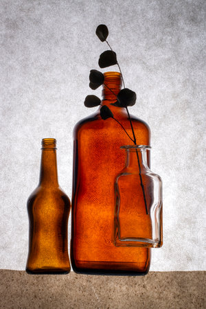 Still life with colored bottles and a dried twigの写真素材