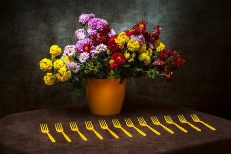 Still life with a bouquet of chrysanthemums in a yellow vase and yellow forksの写真素材