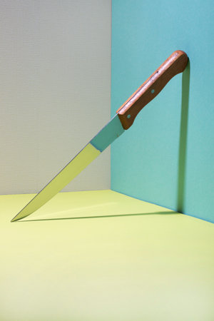 Sharp kitchen knife in the corner on a colored background