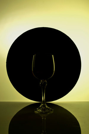 Glass goblet against a black circle