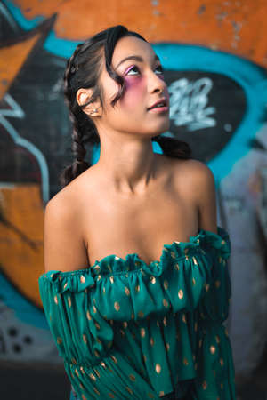 Outdoor urban portrait photograph of a young MÃ©tis girl with pigtails on a graffiti background.