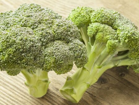 Pieces of broccoli cabbage lie on a wooden table with herbsの写真素材