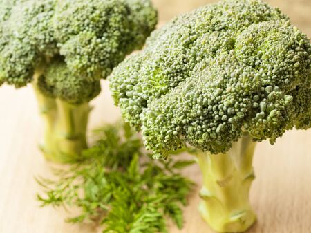 Pieces of broccoli cabbage lie on a wooden table with herbsの写真素材
