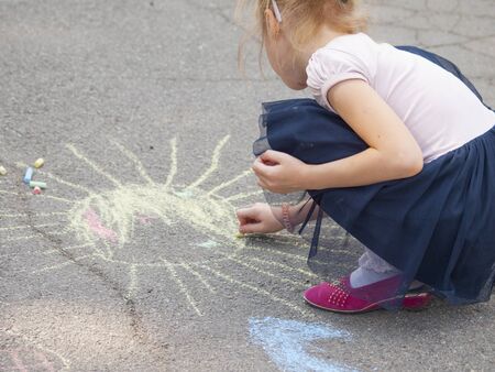 Girl draws with chalk on the pavement drawings