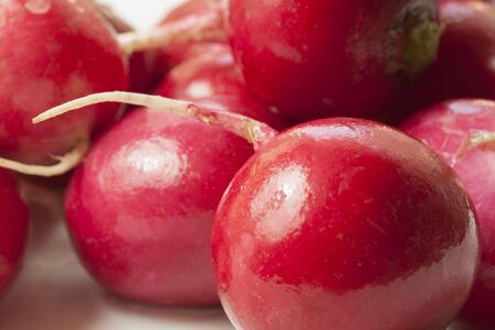 Red radish lies in a bunch on a plate on the table